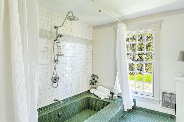 full bathroom with tile patterned flooring, a tile shower, and a healthy amount of sunlight