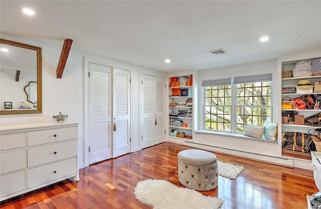 living area featuring a baseboard heating unit, recessed lighting, wood finished floors, and visible vents