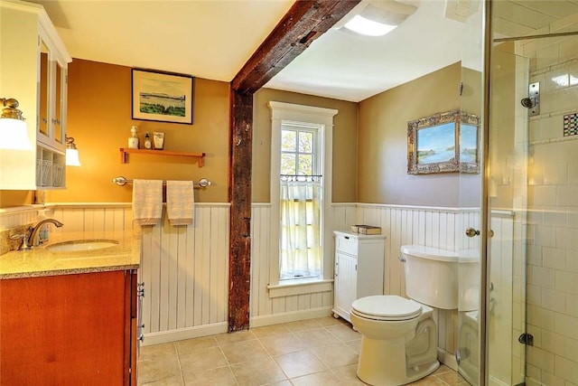 bathroom with tile patterned flooring, a shower stall, a wainscoted wall, beamed ceiling, and toilet