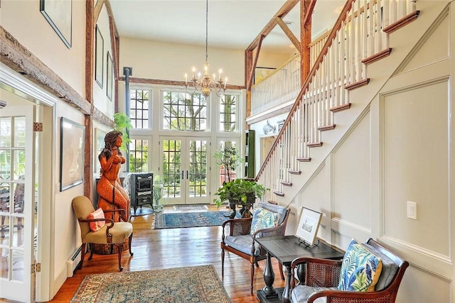 entrance foyer featuring a high ceiling, a notable chandelier, french doors, wood finished floors, and a baseboard heating unit