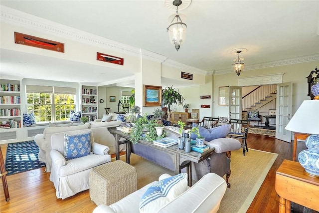 living area with stairs, built in features, ornamental molding, and wood finished floors
