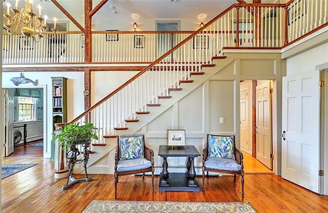 stairs with a chandelier, hardwood / wood-style floors, and a towering ceiling