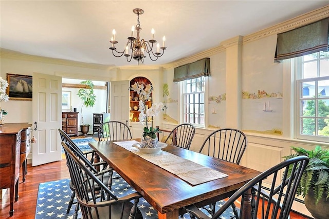 dining space featuring crown molding, plenty of natural light, wood finished floors, and a notable chandelier