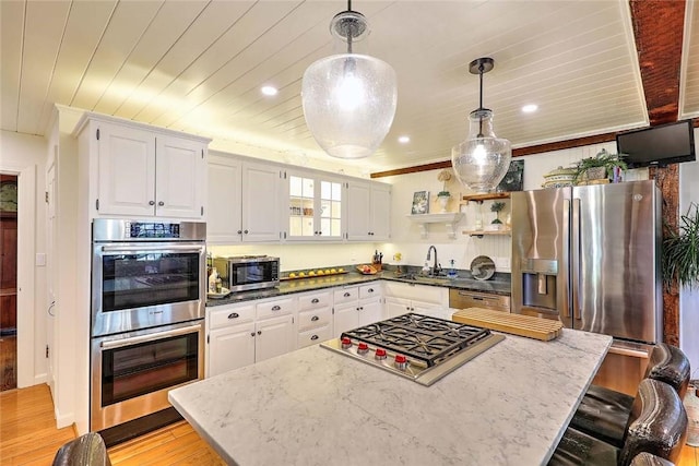 kitchen with white cabinets, stainless steel appliances, a kitchen island, and a sink