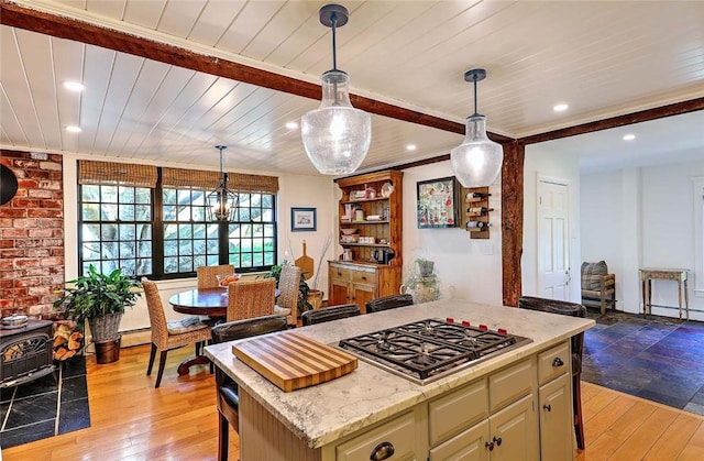 kitchen with light wood finished floors, stainless steel gas cooktop, a kitchen island, and decorative light fixtures
