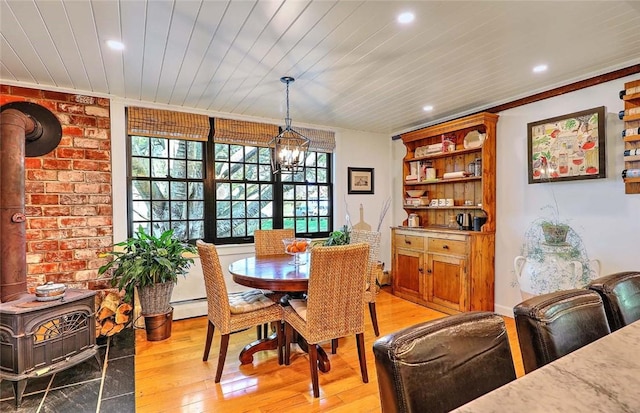 dining space with a wood stove, light wood finished floors, an inviting chandelier, ornamental molding, and recessed lighting