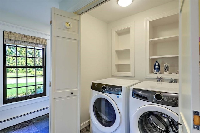 clothes washing area featuring stone finish floor, laundry area, built in features, baseboard heating, and washing machine and dryer