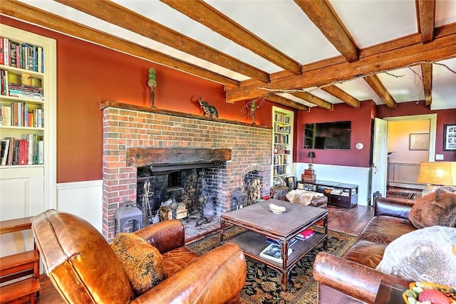 living area with a brick fireplace, wood finished floors, beamed ceiling, a baseboard heating unit, and a wainscoted wall