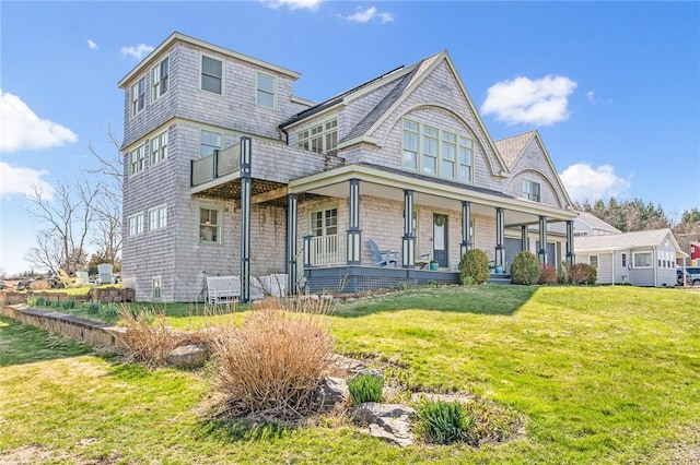 shingle-style home featuring a porch and a front yard