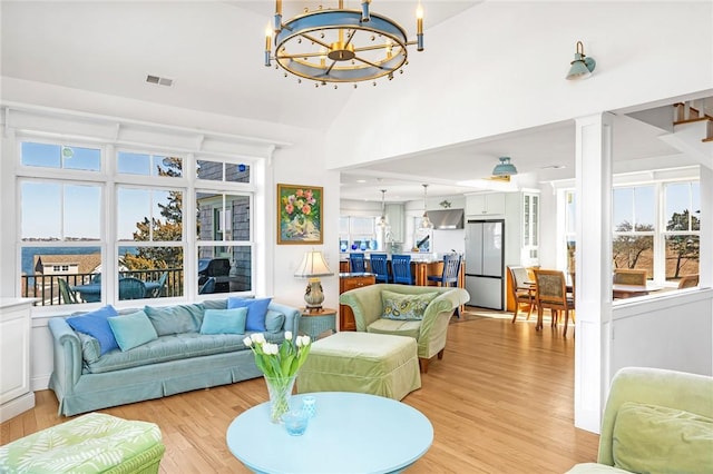 living area with a chandelier, visible vents, decorative columns, and light wood finished floors