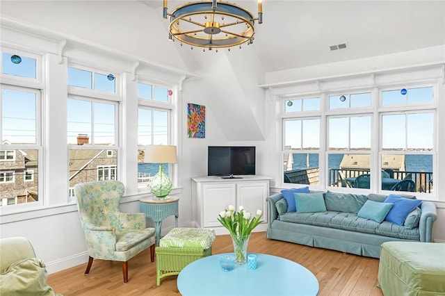 living room with wood finished floors, a chandelier, baseboards, visible vents, and lofted ceiling