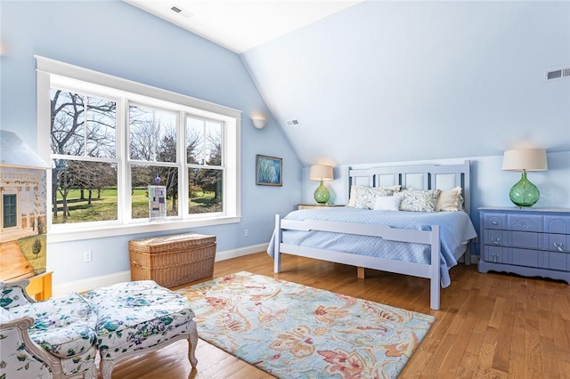 bedroom featuring wood finished floors, visible vents, vaulted ceiling, and baseboards