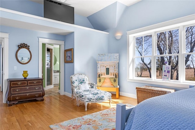 bedroom featuring baseboards, wood finished floors, multiple windows, and vaulted ceiling