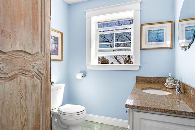 bathroom featuring toilet, tile patterned floors, vanity, and baseboards