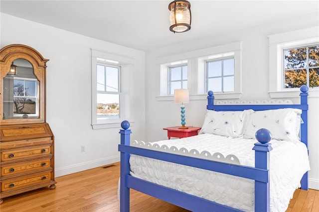 bedroom featuring wood finished floors, visible vents, and baseboards