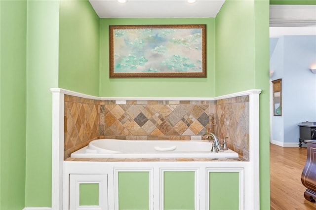 bathroom featuring a garden tub, wood finished floors, and baseboards