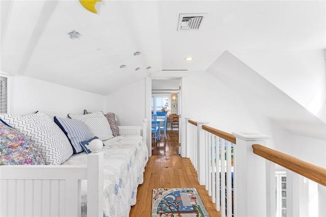bedroom featuring visible vents, vaulted ceiling, and light wood-style floors
