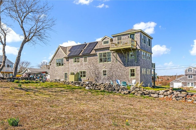 rear view of house with roof mounted solar panels and a balcony