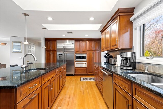 kitchen featuring a sink, built in appliances, tasteful backsplash, a warming drawer, and visible vents