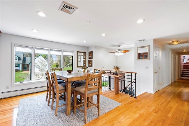 dining room with visible vents, a baseboard heating unit, and light wood-style floors