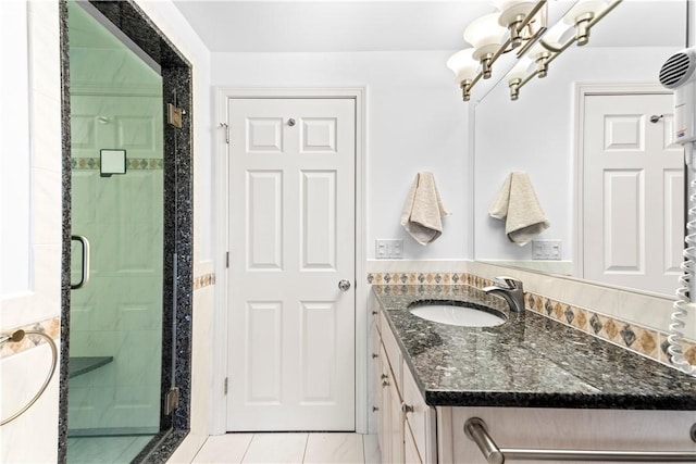 full bathroom with tile patterned flooring, a notable chandelier, a shower stall, and vanity