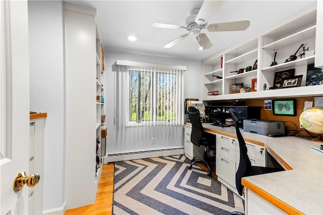 home office featuring a baseboard heating unit, recessed lighting, built in desk, ceiling fan, and light wood-type flooring