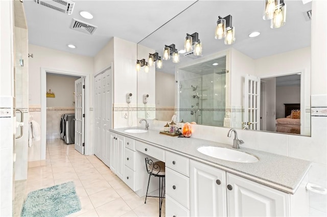 bathroom with visible vents, washing machine and dryer, a shower stall, and a sink