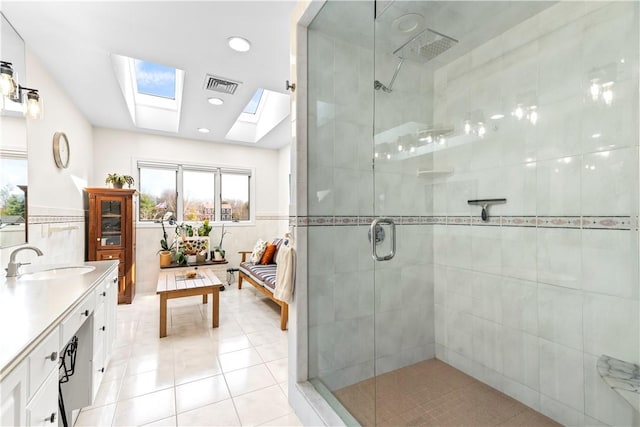 full bathroom with a skylight, visible vents, ensuite bathroom, tile walls, and tiled shower