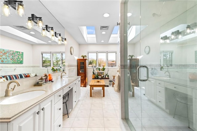 bathroom with a skylight, visible vents, tile patterned flooring, and a sink
