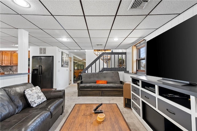living area featuring visible vents, a paneled ceiling, stairs, and light carpet