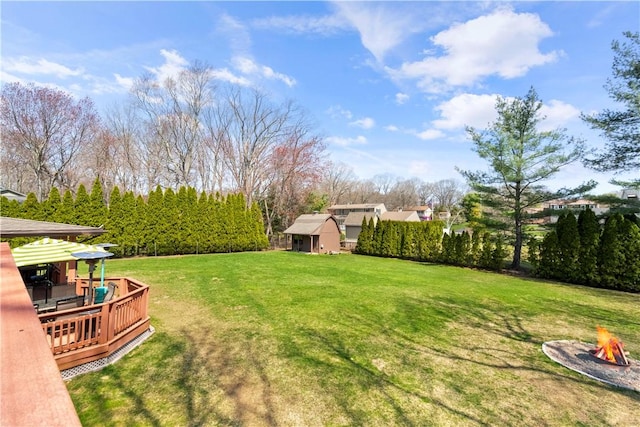 view of yard with a deck, an outdoor fire pit, and an outbuilding