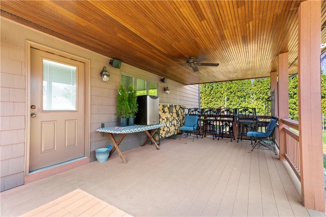 wooden terrace with a ceiling fan and outdoor dining area