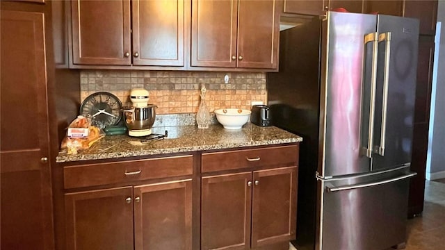 kitchen with backsplash, stone countertops, high end fridge, and brown cabinetry
