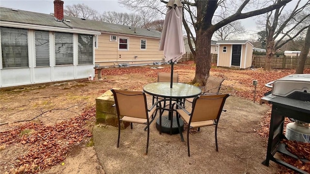 view of patio / terrace with outdoor dining space, fence, an outdoor structure, and a storage shed