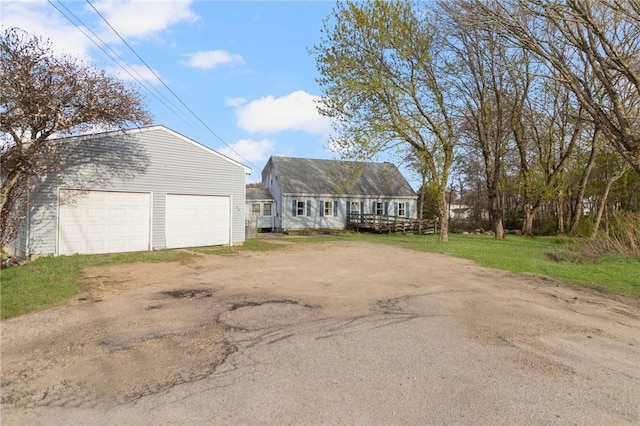 cape cod house featuring a garage and an outbuilding