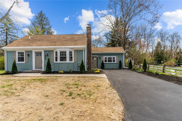 view of front of house with fence, driveway, and a chimney