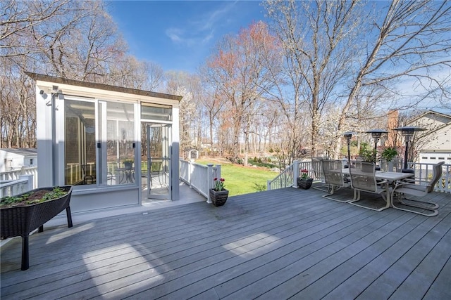 wooden deck with a sunroom and outdoor dining area