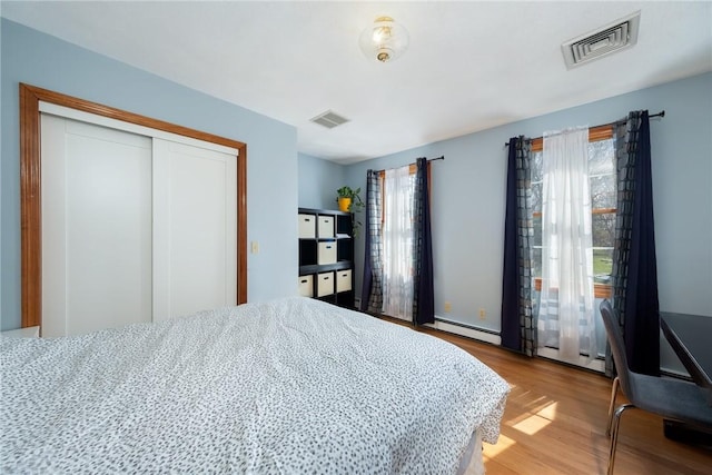 bedroom featuring visible vents, multiple windows, and a baseboard radiator