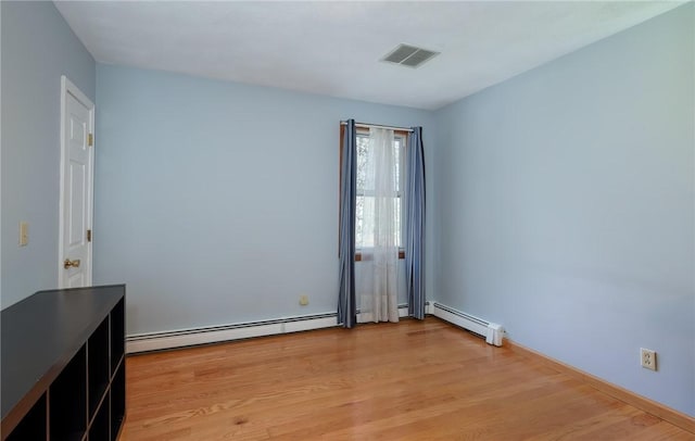 unfurnished room with visible vents, baseboard heating, and light wood-style flooring