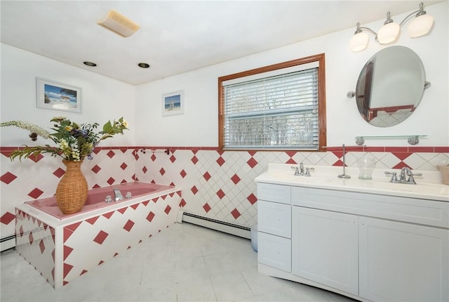 bathroom with tile patterned floors, double vanity, baseboard heating, tile walls, and a sink