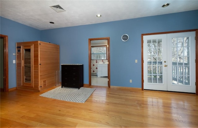 interior space with visible vents, access to exterior, wood finished floors, and french doors
