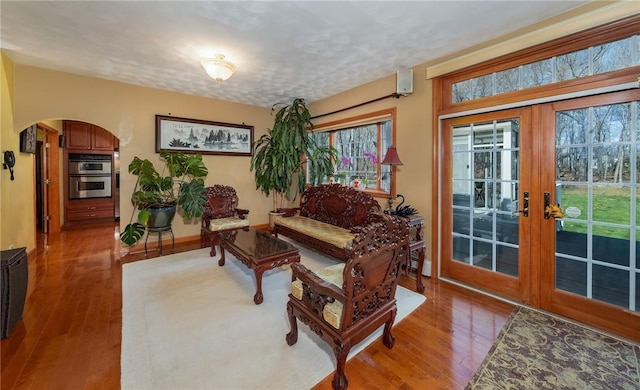 living room featuring wood finished floors, french doors, and arched walkways