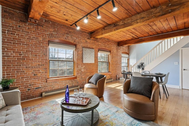 living area with track lighting, a baseboard heating unit, hardwood / wood-style floors, and brick wall