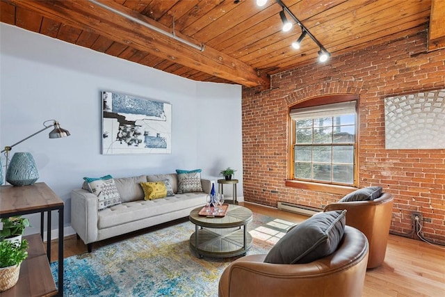 living area with a baseboard heating unit, track lighting, wood finished floors, and brick wall