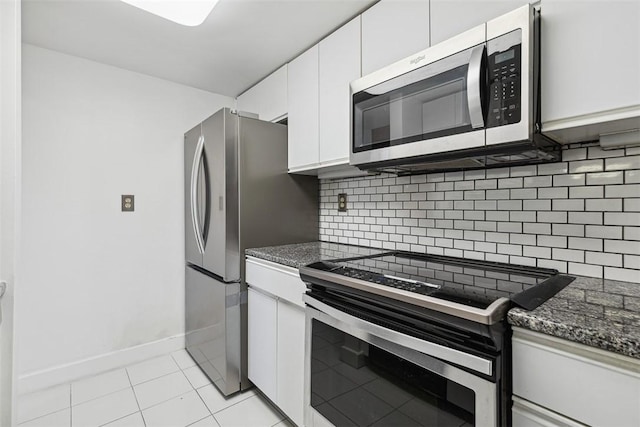kitchen featuring tasteful backsplash, light tile patterned floors, stainless steel appliances, white cabinets, and baseboards