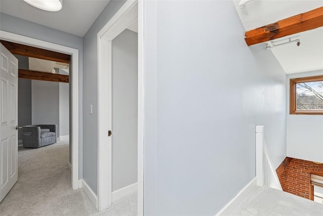 hall featuring baseboards, light carpet, and an upstairs landing