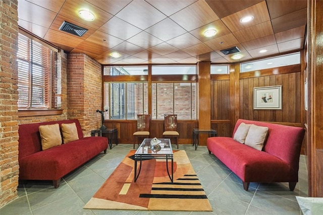 interior space with tile patterned floors, visible vents, brick wall, and wood walls