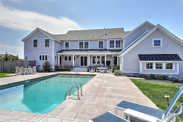 rear view of house featuring fence, a standing seam roof, metal roof, and a patio area