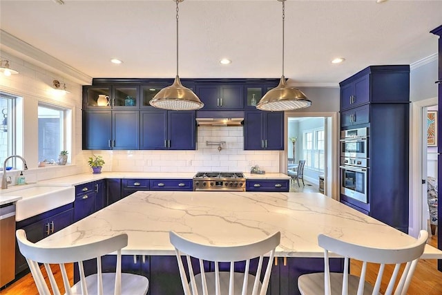 kitchen with a sink, plenty of natural light, stainless steel appliances, a kitchen bar, and blue cabinets
