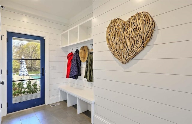 mudroom featuring baseboards, wood walls, and tile patterned flooring